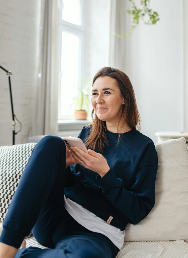 Young woman relaxing at home using her phone