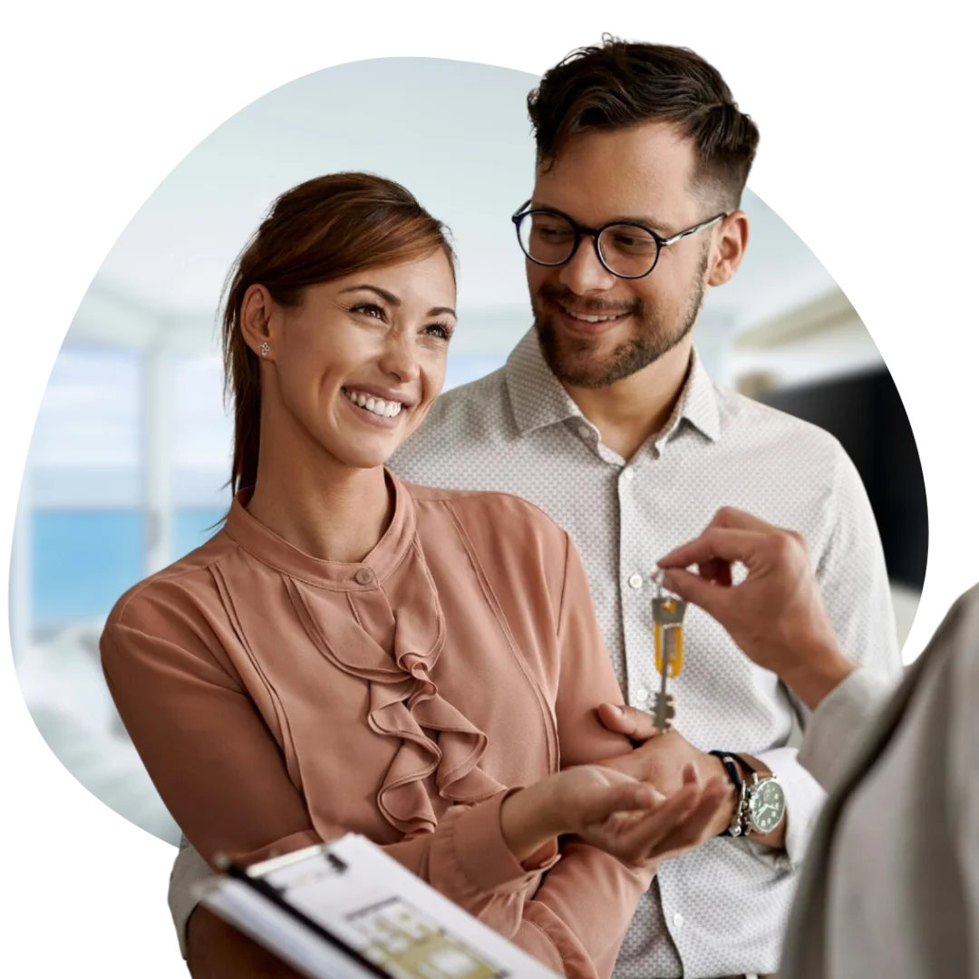 Young couple being handed house keys by a real estate agent after purchasing a property